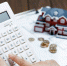 a-female-hand-operating-a-calculator-in-front-of-a-villa-house-model - News102.Ru