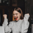 happy-woman-in-glasses-makes-winning-gesture-and-sincerely-rejoices-lady-with-red-lipstick-dressed-in-gray-sweater-looking-at-laptop - News102.Ru